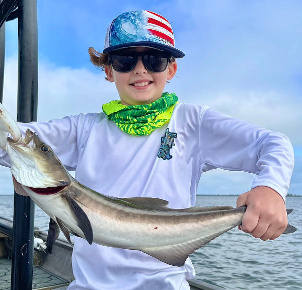 Young Fisherman Holding Up Fish on Boat